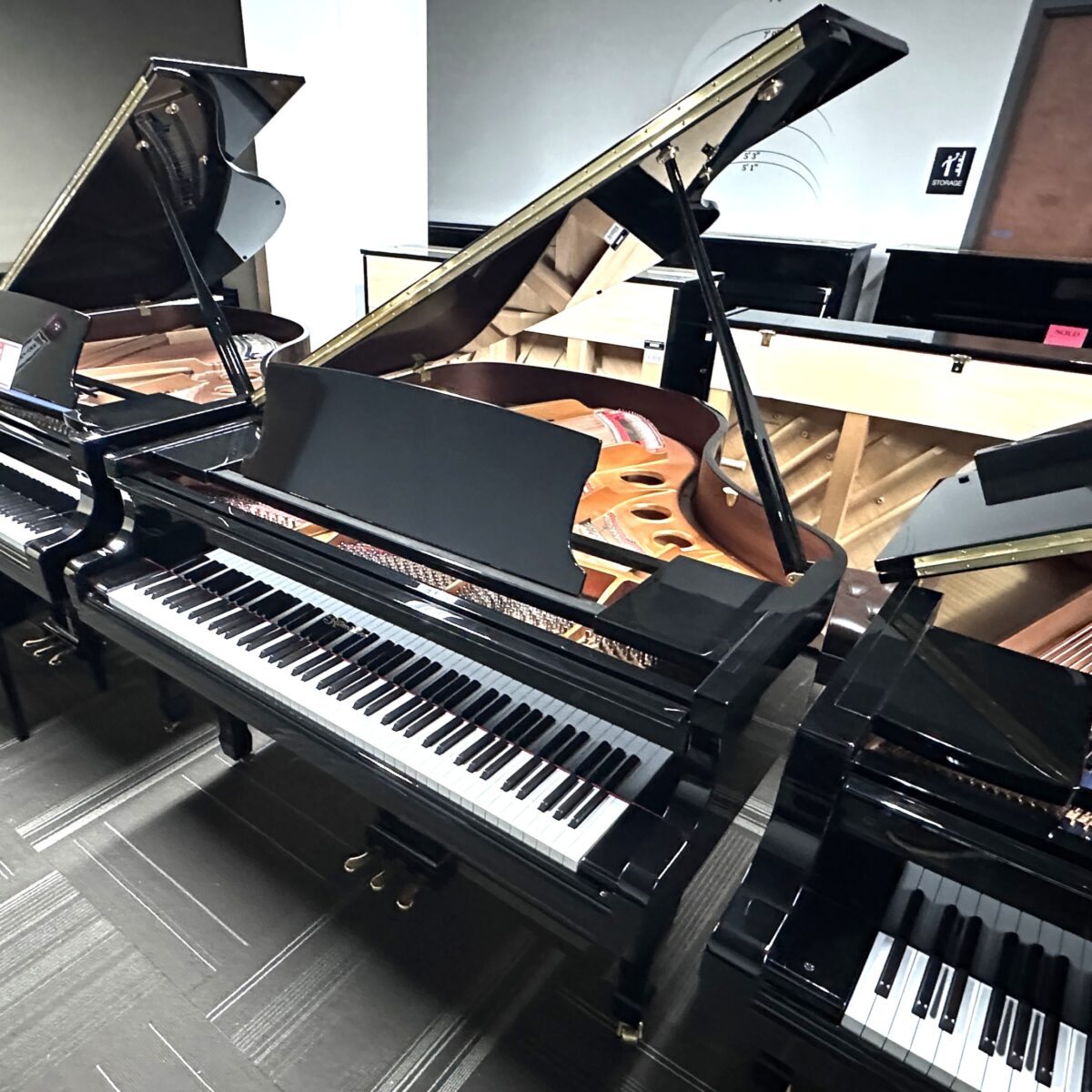 Glossy black grand pianos in Classic Pianos Seattle showroom.