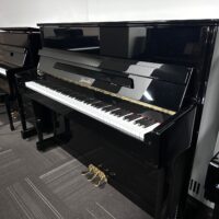 Upright Rippen piano with black gloss finish in a showroom setting.