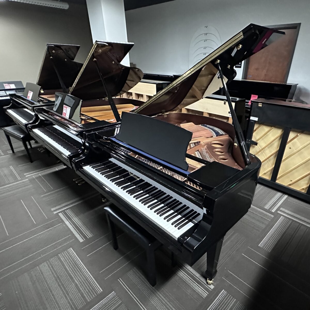Three grand pianos with open lids in a music showroom at Classic Pianos Seattle.