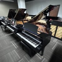 Three grand pianos with open lids in a music showroom at Classic Pianos Seattle.