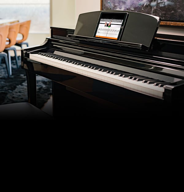 Digital grand piano with a sleek black finish and integrated tablet for interactive learning, ideal for modern musicians.