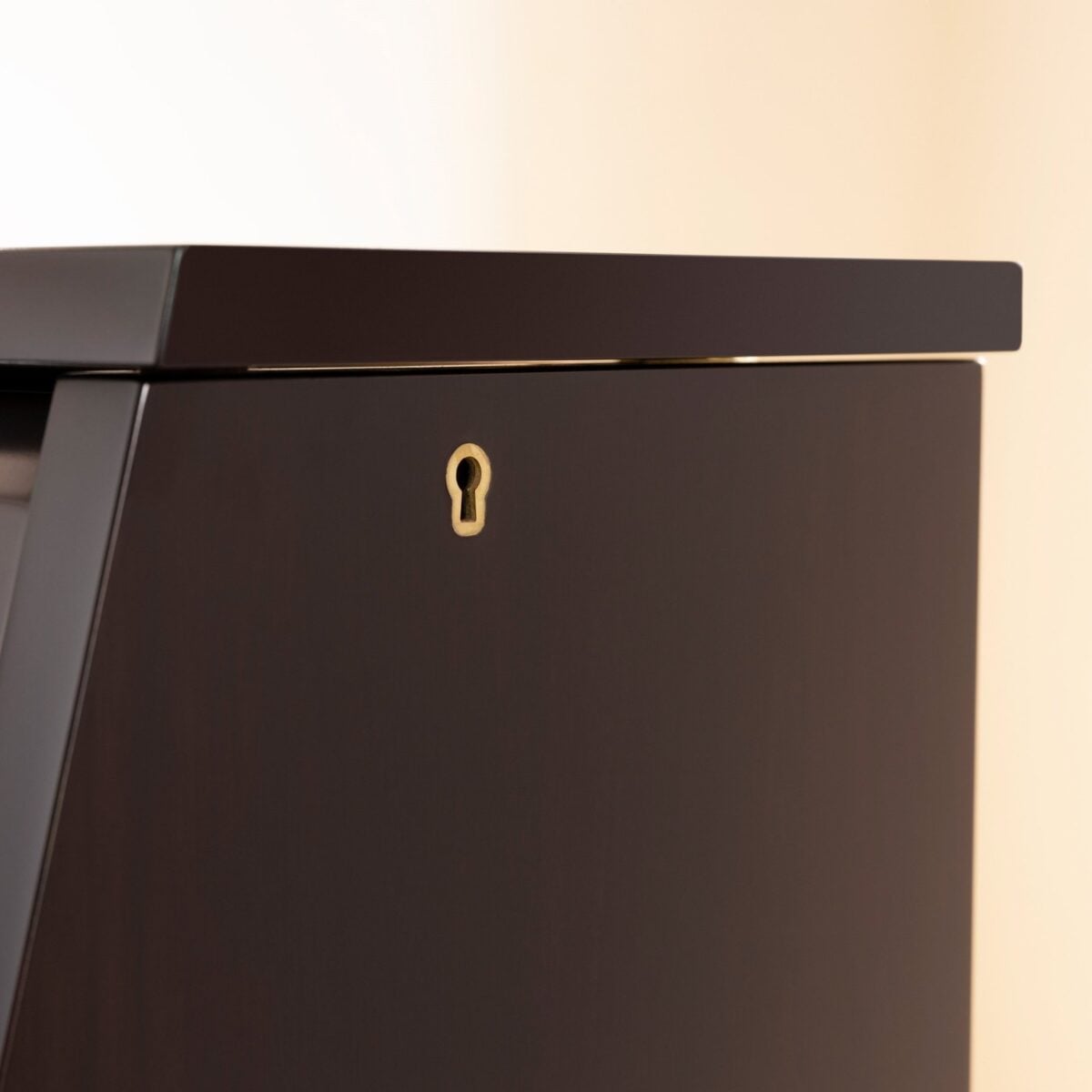 Close-up of a polished ebony piano cabinet corner with keyhole detail, showcasing fine craftsmanship at Classic Pianos