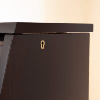 Close-up of a polished ebony piano cabinet corner with keyhole detail, showcasing fine craftsmanship at Classic Pianos