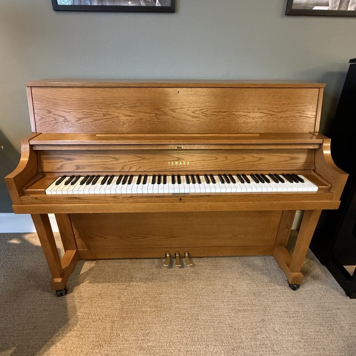 Yamaha console piano in oak finish, featuring responsive keys and three pedals for enhanced playing experience.