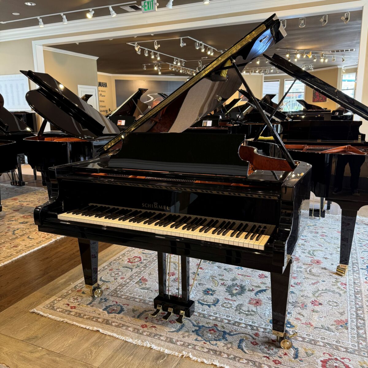Alt text: Schimmel grand piano featuring polished black finish and ebony keys, showcased in a premium piano showroom.