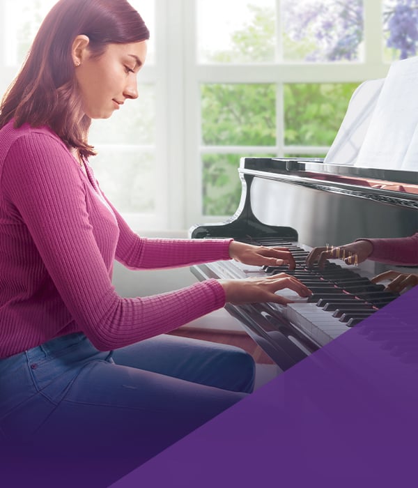 Young woman playing a polished black grand piano, emphasizing the rich sound and craftsmanship typical of Classic Pianos.