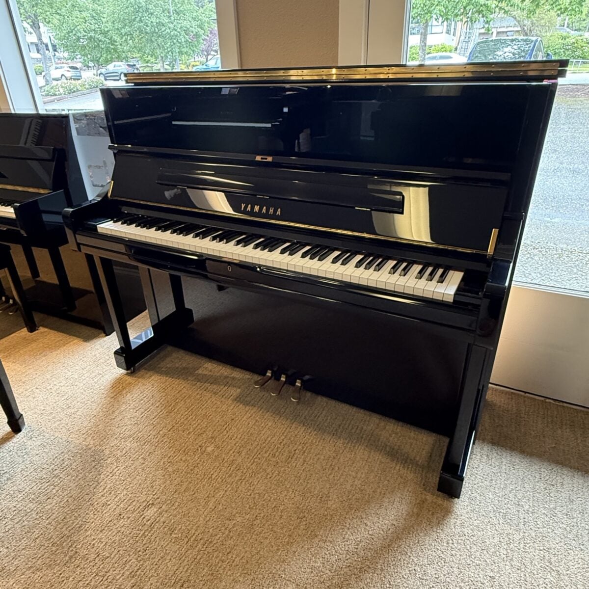Yamaha upright piano with polished ebony finish, featuring high-quality keys and craftsmanship, perfect for any pianist.