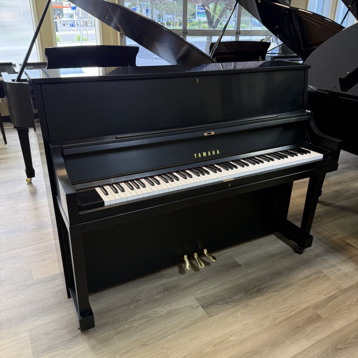 Alt text: Yamaha upright piano in black finish with white keys and gold pedals, showcasing quality craftsmanship at Classic Pianos.