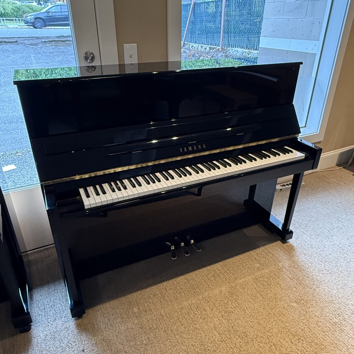 Yamaha upright piano in polished black finish, featuring a full keyboard and responsive action, ideal for any musician.