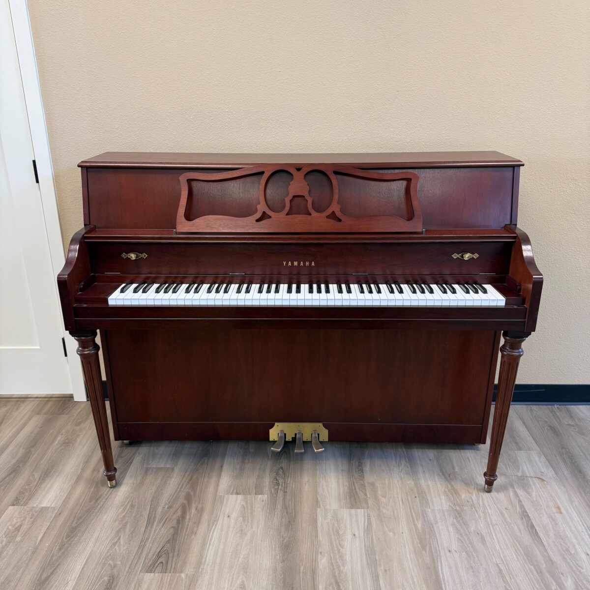 Yamaha console piano in polished mahogany finish with elegant detailing and classic white keys, perfect for any musician.