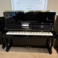 Alt text: Yamaha upright piano with glossy black finish and classic white keys, showcasing superior craftsmanship and sound quality.