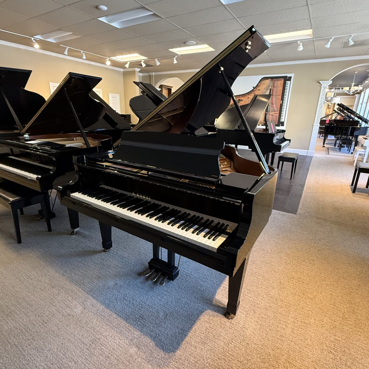 Showcasing a polished Kawai grand piano with an ebony finish, featuring a responsive action and rich sound quality.