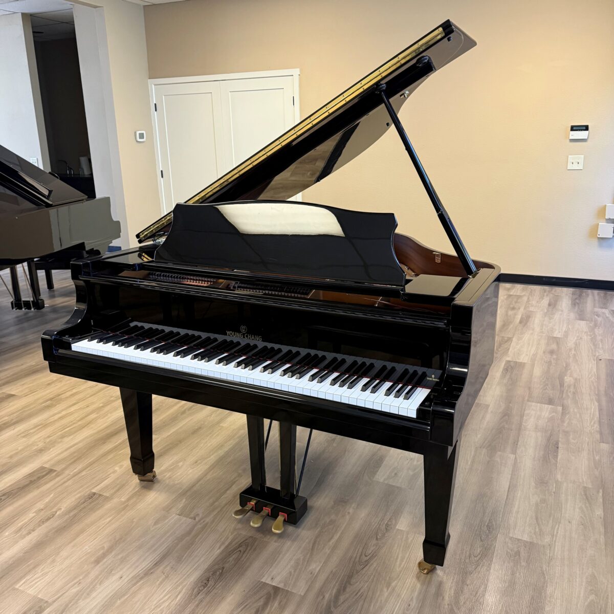 Alt text: Young Chang grand piano with polished ebony finish and precision action, showcased in a modern showroom setting.