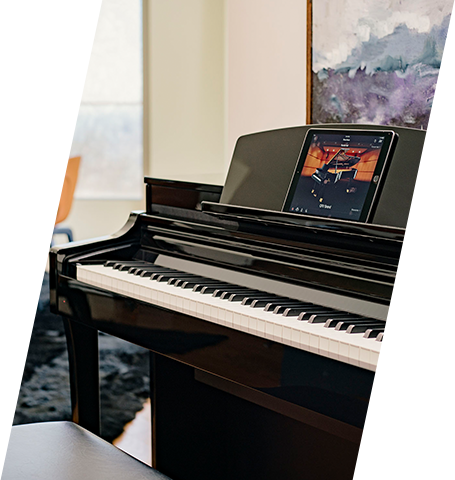 Digital piano with glossy black finish, featuring display screen, in a contemporary showroom setting.