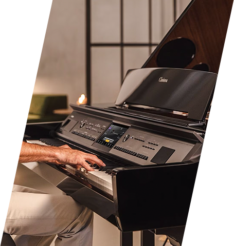 Man playing a Yamaha digital grand piano in a modern showroom setting.